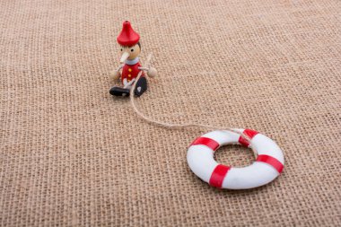 Pinokyo bebeği tuvaldeki can yeleğine bağlı.