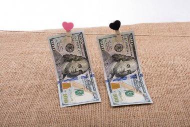 100 dolarlık banknotlar ve bir kalp klipsi.