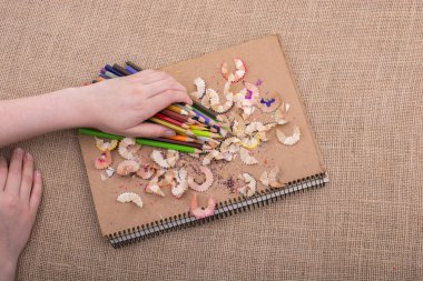 Kalem talaşı içeren bir defterin üzerine renkli kalemler