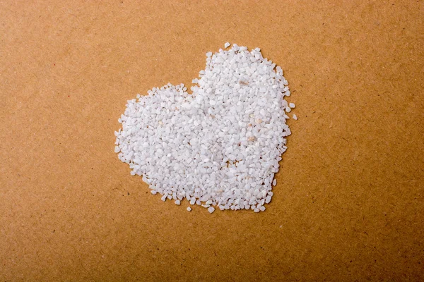 Beyaz Kum Taşı Kahverengi Arkaplanda Bir Kalp Şekli Oluşturur — Stok fotoğraf