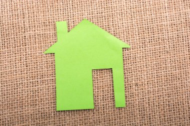 Tuvalin arka planında kağıttan yapılmış küçük bir ev şekli.