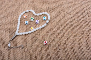 Dua eden bir boncuğun içinde ellerinde kalp şeklinde küpler.