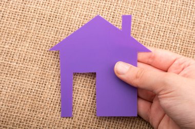 Tuvalin arka planında bir bez evi tutan el.