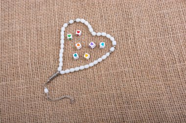 Dua eden bir boncuğun içinde ellerinde kalp şeklinde küpler.