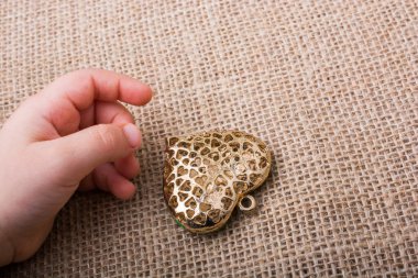 Altın rengi metal nesne bir el yanında kalp şeklinde