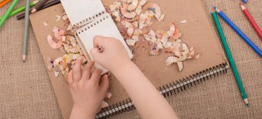 Spiral defter üzerinde bir renk kalem tutan el 