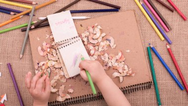 Spiral defter üzerinde bir renk kalem tutan el 