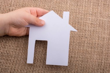 Tuval üzerinde bir kağıt ev tutan el 