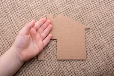 Tuvalin arka planında bir bez evi tutan el.