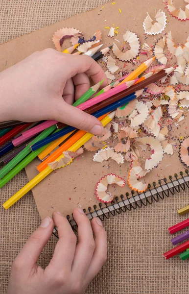 Renkli kalemler üzerinde bir defter tutan el