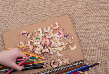 Bir defter kalem talaş ile üzerinde renkli kalemler tutan el
