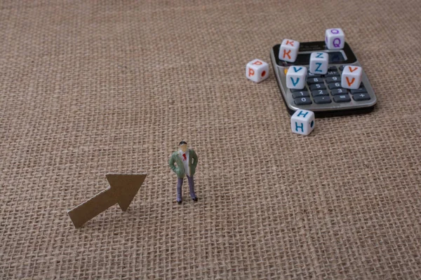 Renkli harf küpleri ve bir heykelciğin yanında hesap makinesi