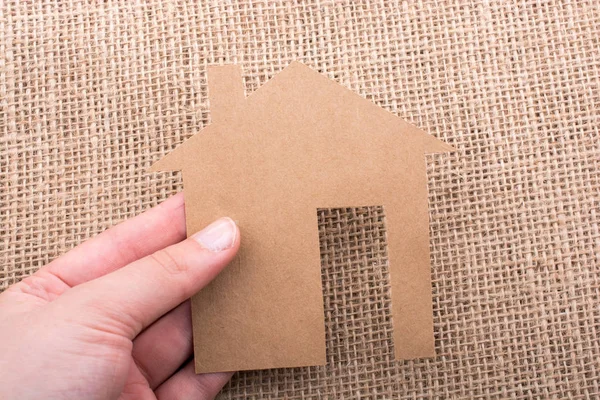 Tuval üzerinde bir kağıt ev tutan el 