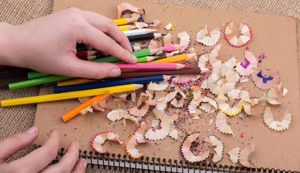 Renkli kalemler üzerinde bir defter tutan el