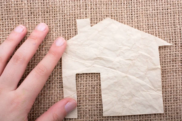 Tuval üzerinde bir kağıt ev tutan el 