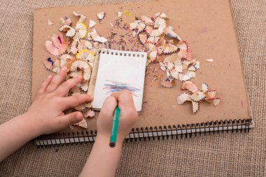 Spiral defter üzerinde bir renk kalem tutan el 