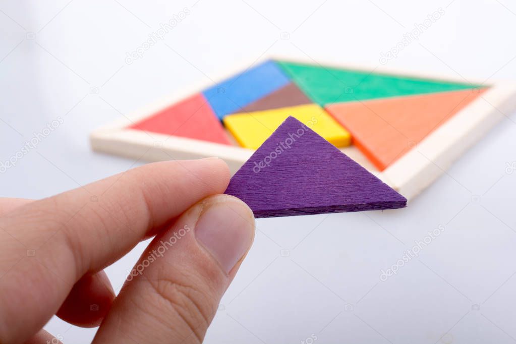 hand holding a missing piece in a tangram puzzle