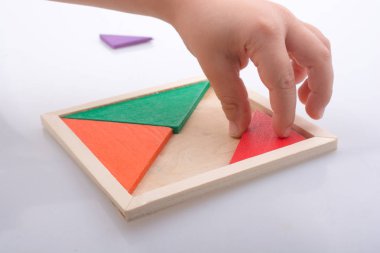 Tangram bulmacasının kayıp parçasını tutan el.