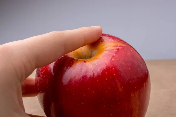 Ręka trzyma Czerwone jabłko na drewno — Zdjęcie stockowe