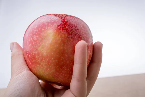 Χέρι που κρατά ένα κόκκινο μήλο σε ξύλο — Φωτογραφία Αρχείου