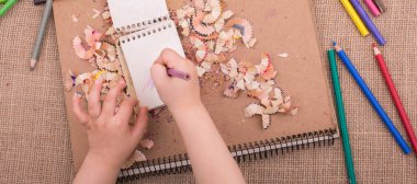 Spiral defter üzerinde bir renk kalem tutan el 