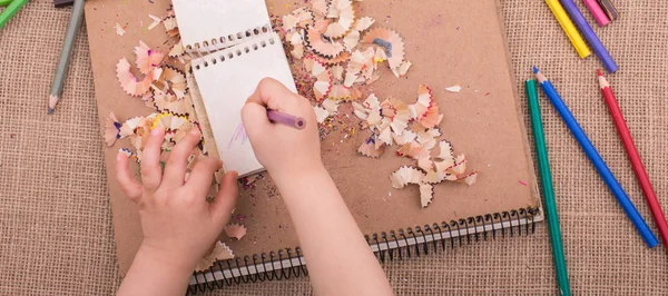 Spiral defter üzerinde bir renk kalem tutan el 