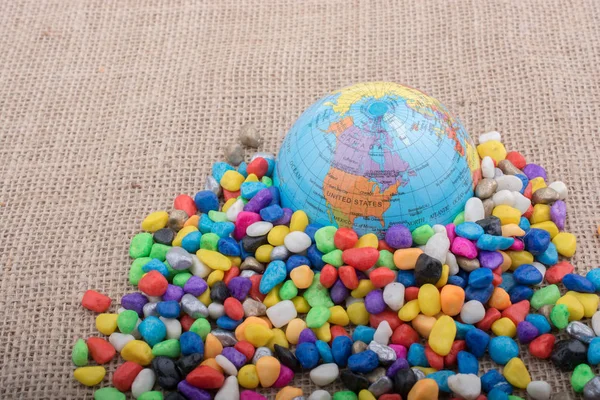 Маленький модельный глобус среди разноцветной гальки — стоковое фото