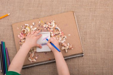 Spiral defter üzerinde bir renk kalem tutan el 