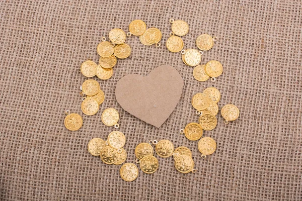 Fake gold coins around heart shape made of paper