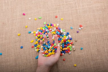 Elindeki ve yerdeki renkli çakıl taşları