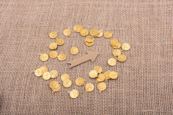 Fake gold coins around arrow shape made of paper