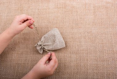 Çarşaftan yapılmış boş bir çuvalı tutan el.