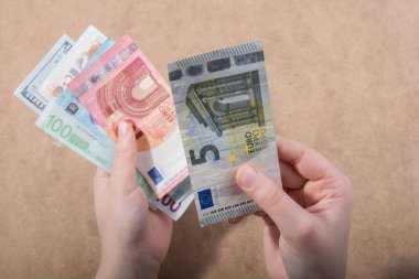 El ele tutuşan Amerikan doları banknotları ahşap arka planda izole edilmiş.