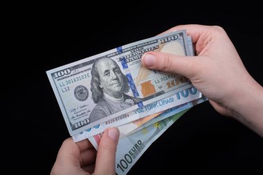 El ele tutuşan Amerikan doları banknotları siyah arka planda izole edilmiş.
