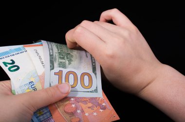 El ele tutuşan Amerikan doları banknotları siyah arka planda izole edilmiş.