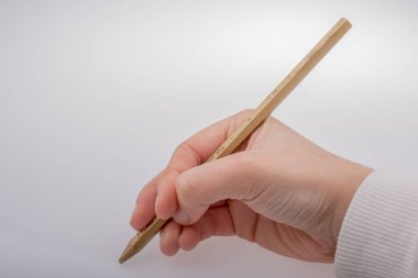 Beyaz arka planda altın renkli bir kalem tutuyor.