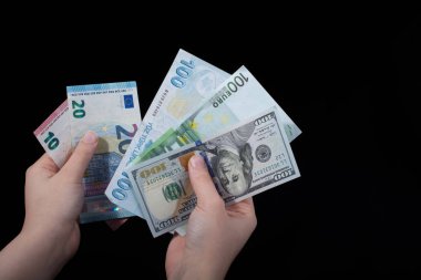 El ele tutuşan Amerikan doları banknotları siyah arka planda izole edilmiş.