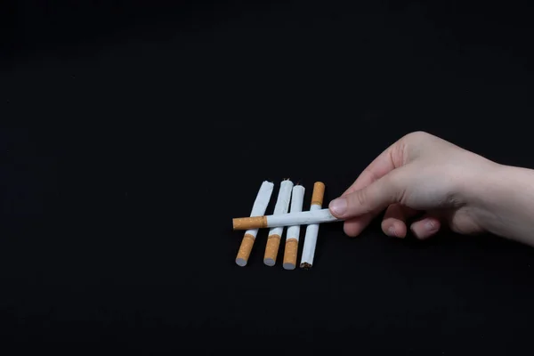 Hand Hält Gekreuzte Zigaretten Auf Schwarzem Hintergrund — Stockfoto