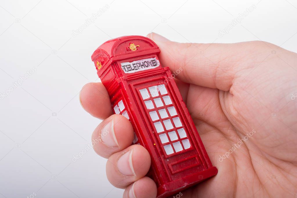 Hand holding a red color phone booth on a white background