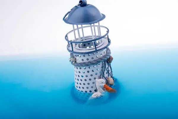 青い水に置かれた小さなモデル灯台 — ストック写真