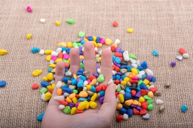 Elindeki ve yerdeki renkli çakıl taşları