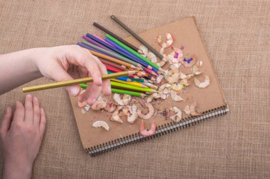 Kalem talaşı olan bir defterin üzerinde Renkli Kalem 'i tutarken