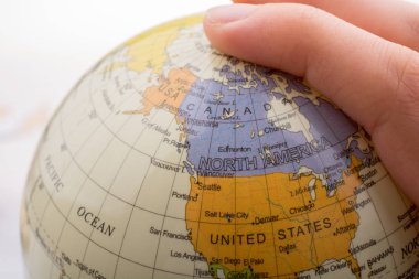 Üzerinde harita olan bir küreyi tutan el.