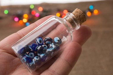 Hatıra olarak şişede nazar boncuğu tutan el.