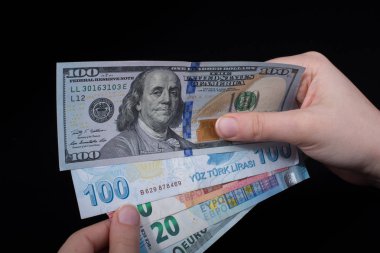 El ele tutuşan Amerikan doları banknotları siyah arka planda izole edilmiş.