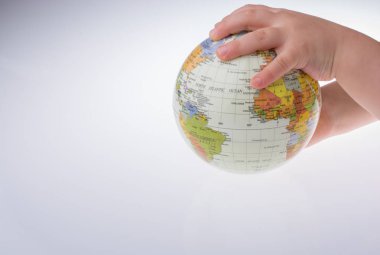 Beyaz arka planda bir küreyi tutan çocuk