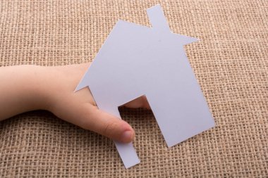 Tuvalin arka planında bir bez evi tutan el.