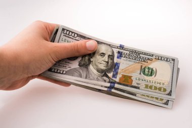İnsan eli, Amerikan doları banknotunu beyaza izole edilmiş olarak tutuyor.