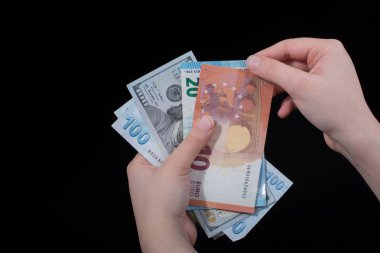 El ele tutuşan Amerikan doları banknotları siyah arka planda izole edilmiş.