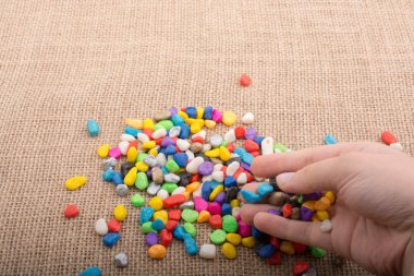 Elindeki ve yerdeki renkli çakıl taşları